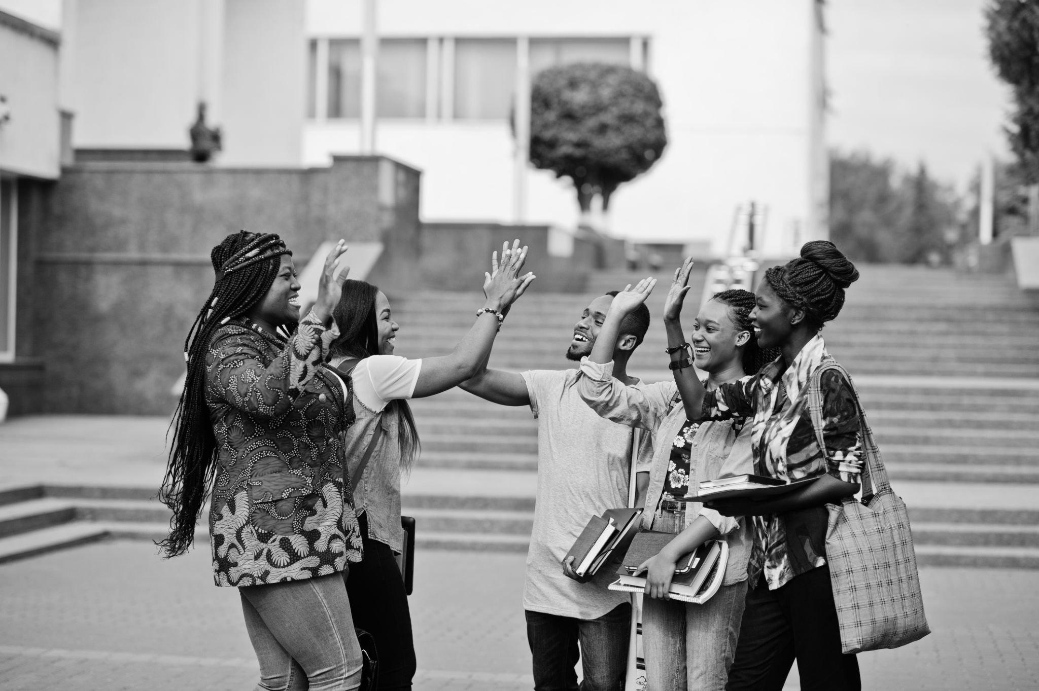 Group of happy international students posing outdoors near school building
